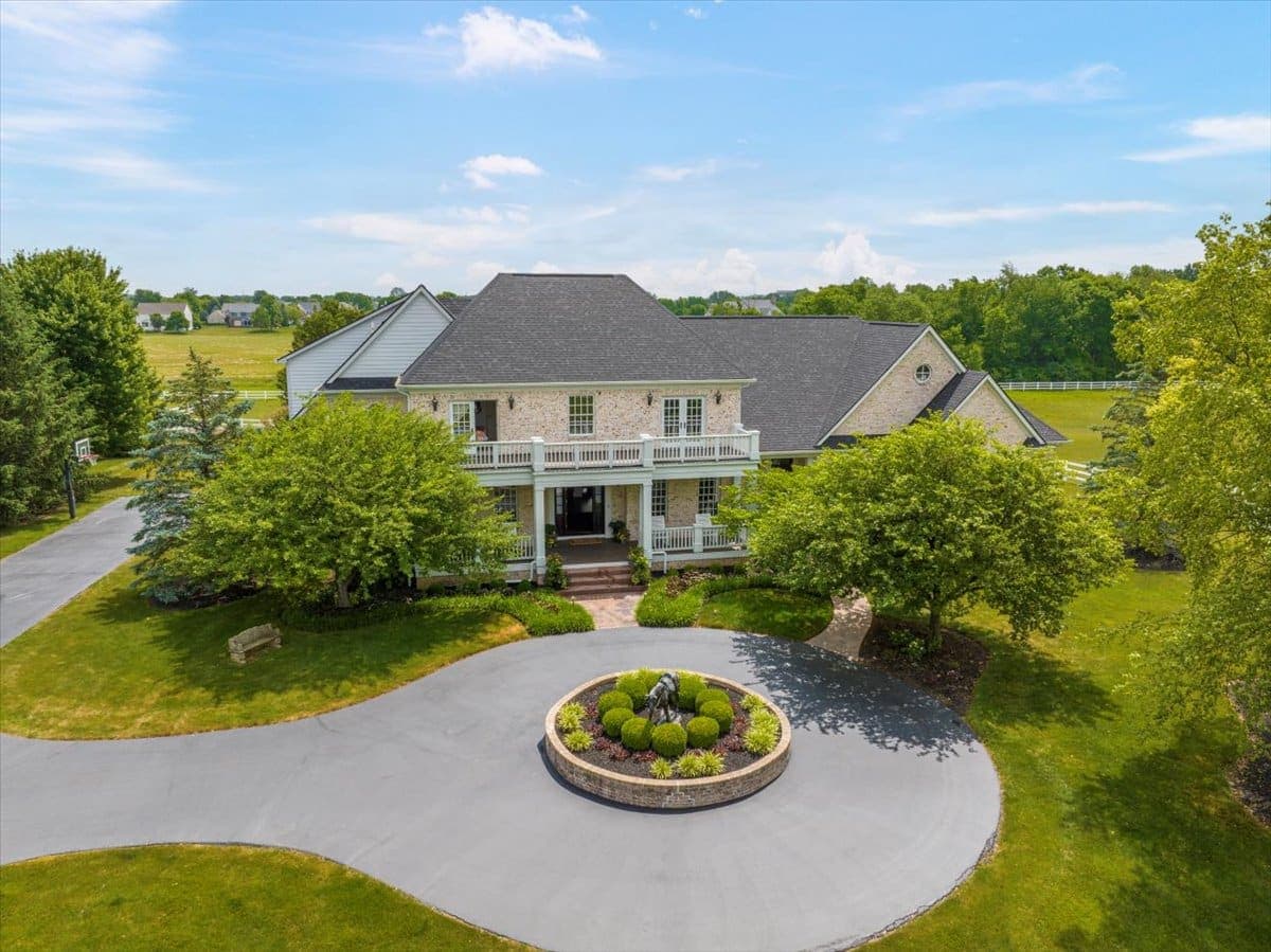 Aerial of a country estate with circular drive, landscaped island, and outbuildings