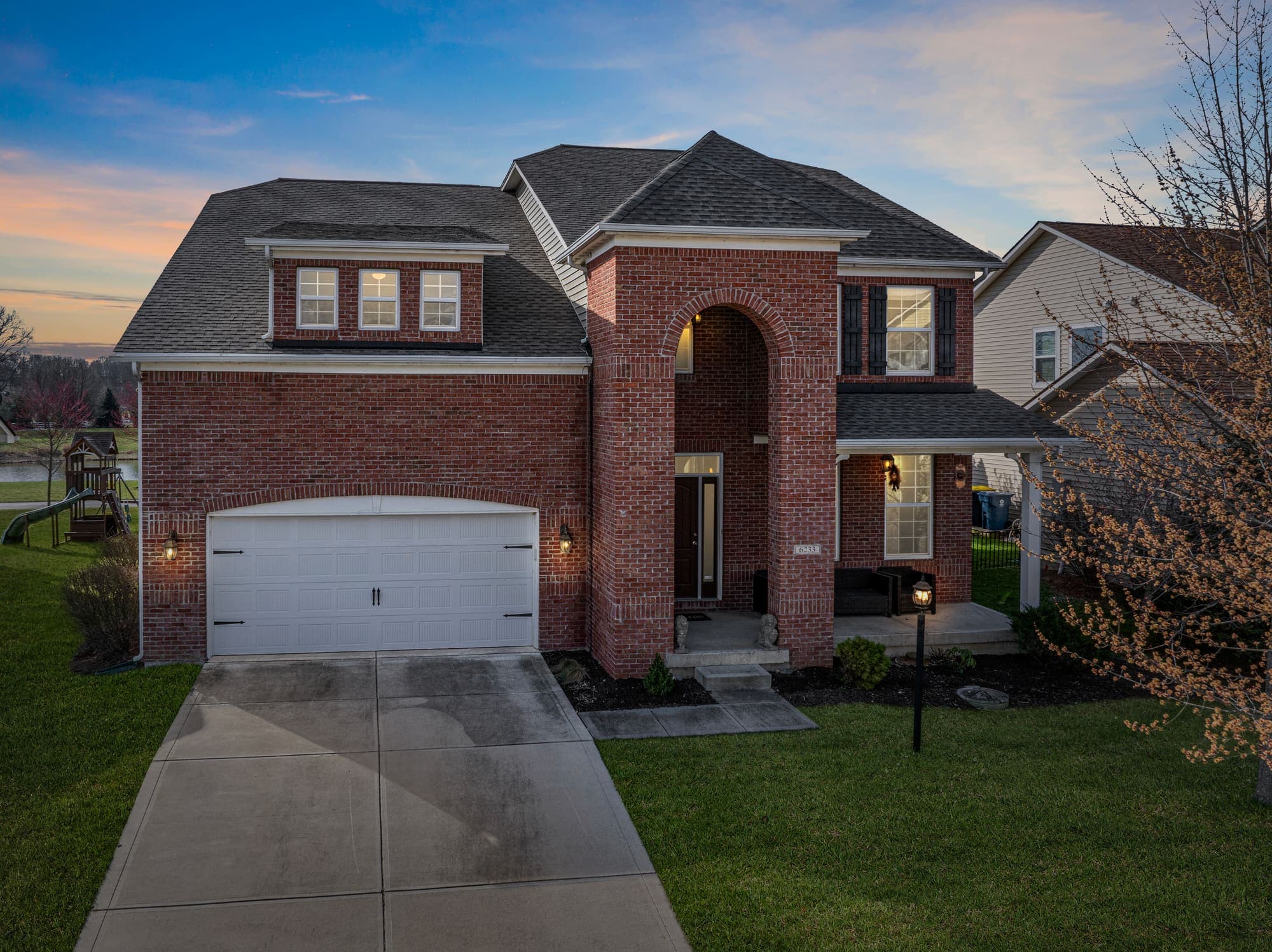 Elevated front view of a brick two-story home at dusk