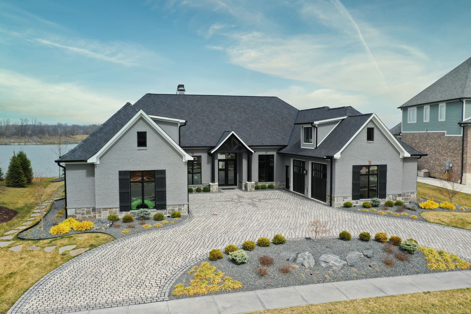 Dusk aerial of a stone and siding estate with a circular paver courtyard