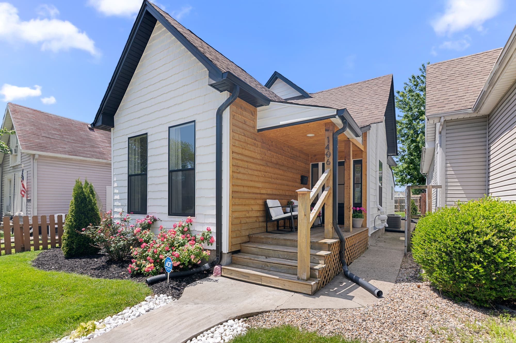 Street view of a renovated white cottage between neighboring homes